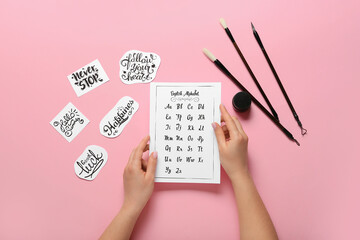 Woman with English alphabet and brushes on pink background