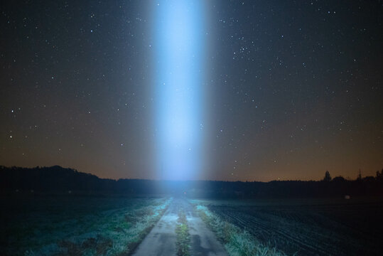Smuga światła nad polną drogą, na tle nocnego, gwieździstego nieba.