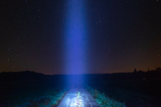 Smuga światła nad polną drogą, na tle nocnego, gwieździstego nieba.