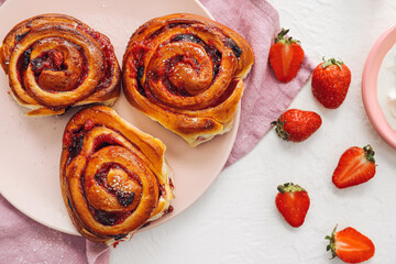 Plate with tasty strawberry buns on white background