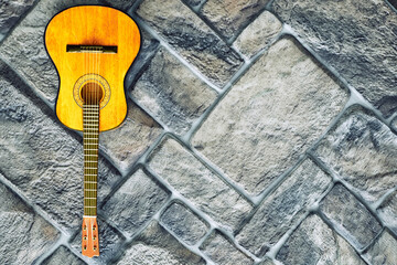 Acoustic yellow guitar on gray brick pavement