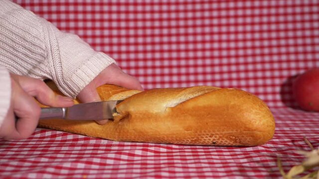 Slicing a white fresh baguette on gingham background