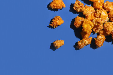 Crunchy popcorn chicken on blue background