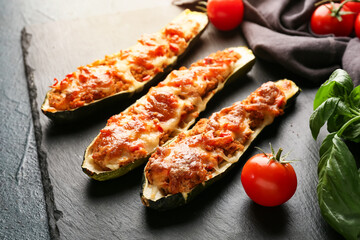 Board with meat stuffed zucchini boats on dark background