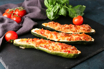 Board with meat stuffed zucchini boats on dark background