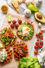 Composition with tasty Belgian waffles and vegetables on light background