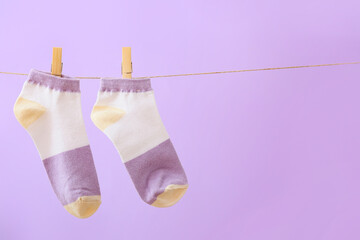 Pair of socks hanging on rope against lilac background