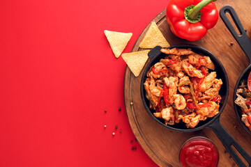 Frying pan with tasty chicken Fajita on red background