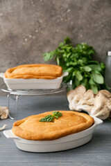 Baking dishes with tasty mushroom pot pie on table