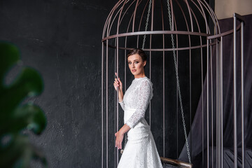 Obraz premium Fashion bride in an iron cage, unhappily looking out from behind bars. Life out of will.