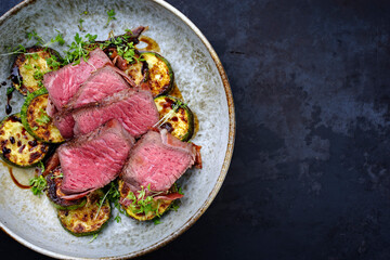 Modern style traditional fried dry aged angus beef filet medaillons with zucchini and cress served...