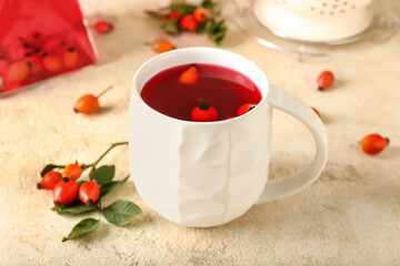 Cup of tasty rose hip tea on light background