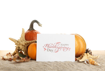 Pumpkins, starfish, seashells and card with text HAPPY THANKSGIVING DAY on sand against white...