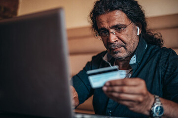 Senior hispanic cuban men using laptop and a credit card while online shopping
