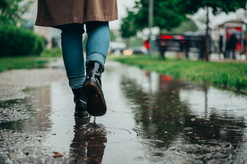 Woman legs walking on puddles while it rains in the city