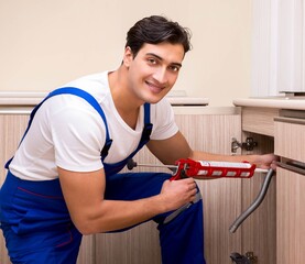 Young repairman working at the kitchen