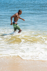 Waving arms, a well built young sexy black guy, half naked,  is running on water of ocean. .