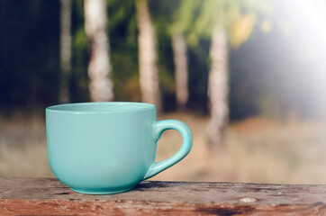 A cup of tea stands on a wooden table against the background of nature. Space for text, copy-space.