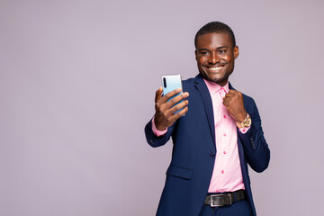 young african businessman using his phone rejoicing