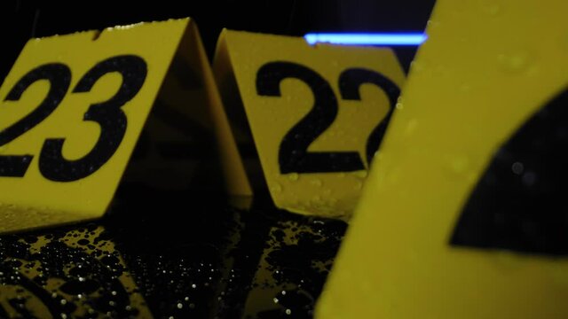 CRIME SCENE MARKERS.  4K, ECU, MACRO SLIDER SHOT.  NIGHT EXTERIOR IN THE RAIN.