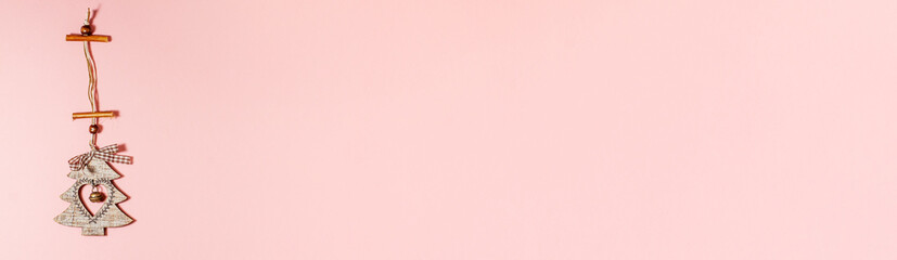 Banner of flat lay of wooden christmas decoration tree with heart inside it and jingle bell on pink. Christmas holidays concept from above with copy space