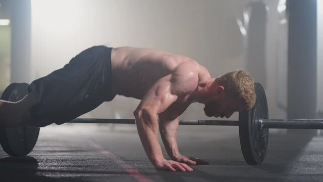 Man doing burpee workout at fitness studio. High-intensity interval training. Young man practicing burpee exercise