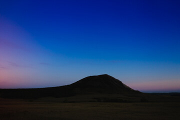 Mountain at night with stars shining and sunset.