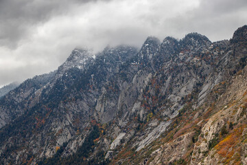 Fototapeta na wymiar Granite mountains ascending into the clouds in Little Cottonwood Canyon, Utah during Autumn
