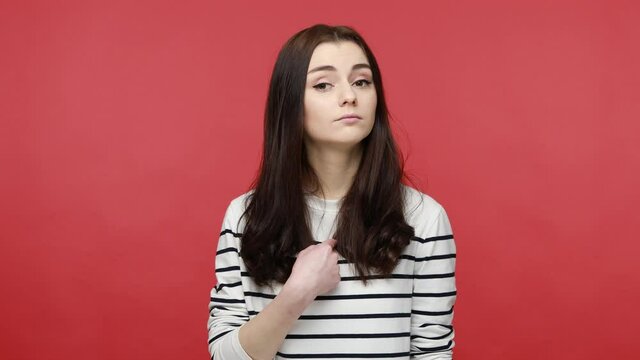 Portrait of confident brunette woman pointing finger on herself, bragging with achievements, egoism, wearing casual style long sleeve shirt. Indoor studio shot isolated on red background.