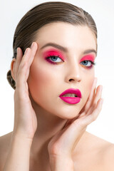Obraz na płótnie Canvas Beautiful young woman’s face with perfect skin, long eyelashes and bright vivid pink make up. Portrait of fashion beauty model with colorful professional makeup