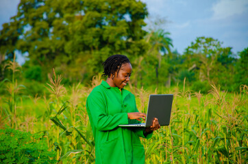 beautiful african agriculturist smiling as she uses her laptop