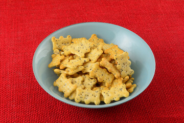 Poppy seed crackers in blue snack bowl on red tablecloth