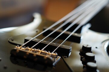 Fototapeta na wymiar Closeup shot of a black bass guitar body with jazz bass style bridge, pickups, knobs and strings