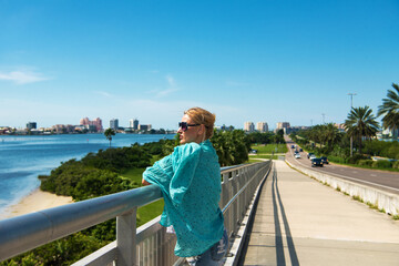 Fototapeta premium Young woman wearing glasses enjoys the view of the clearwater bay