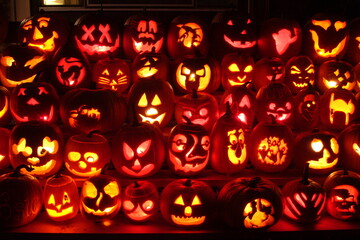 A lot of Halloween pumpkins lit with candles and with scary and happy faces at night