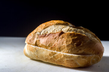 traditional bread on a white board with black background, copy space and selective focus.