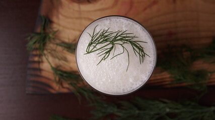 Turkish or Azerbaijan traditional Drink Ayran or Kefir with herbs and dill in a glass on a wooden table top view. Fermented milk drink for diet. Copy space. the concept of healthy nutrition.