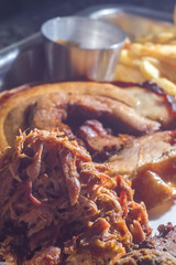 american barbecue tray with porchetta, pulled pork, coleslaw salad, brisket, barbecue sauce, pulled pork dumpling, french fries, selective focus