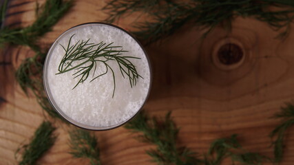 Fototapeta na wymiar Turkish or Azerbaijan traditional Drink Ayran or Kefir with herbs and dill in a glass on a wooden table top view. Fermented milk drink for diet. Copy space. the concept of healthy nutrition.