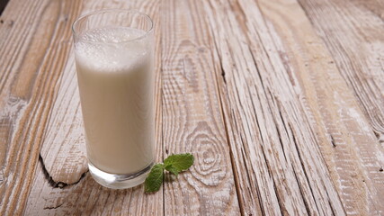 Turkish or Azerbaijan traditional Drink Ayran or Kefir with herbs and with mint in a glass on a wooden table front view. Fermented milk drink for diet. Copy space. the concept of healthy nutrition.