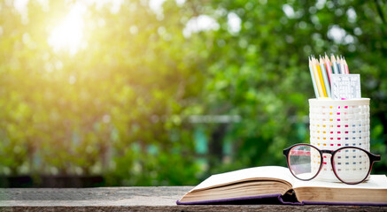 Back to school background with books, pencil and ruler on green blurred backgrounds with copy space.