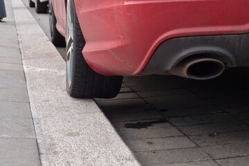 A tire of a red car is on a curb in Moscow - obrazy, fototapety, plakaty