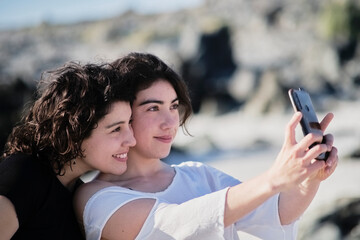 Fototapeta premium sisters taking a selfie on the beach on a beautiful sunny day