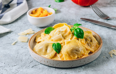 Homemade Pumpkin Ravioli with sauce and bsil on concrete background. Autumn food concept. Selective focus