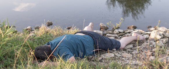 a lifeless dead body lies on the shore of a lake, a young man killed by water