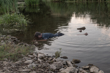 the body of a man who drowned lies face down in the water, the lifeless body of a murdered young man on the river