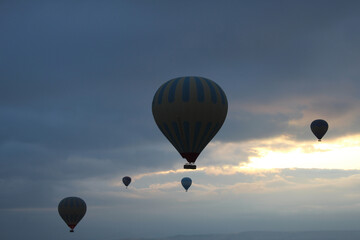 five balloons in flight with hot air, against a background of blue clouds and bright glimpses of sunset