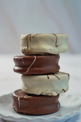 White and brown chocolate alfajores on porcelain plate.