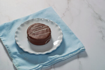 Detail of chocolate alfajor on an elegant plate. Argentinian pastries