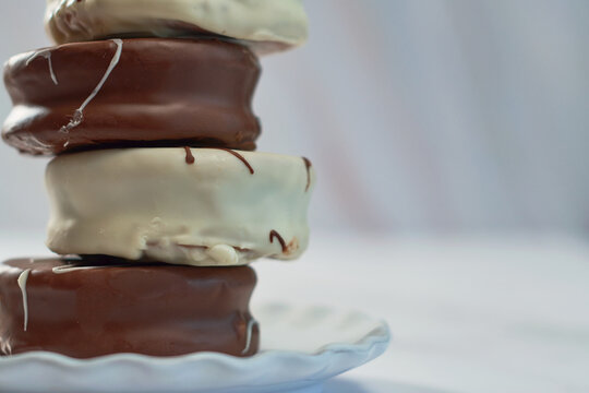White and brown chocolate alfajores on porcelain plate.